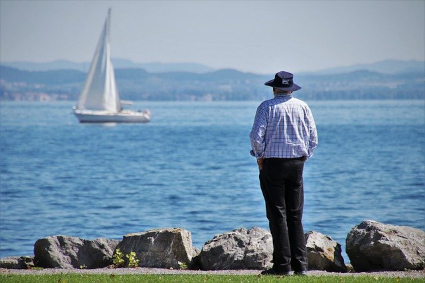 Un homme observe un voilier sur le lac